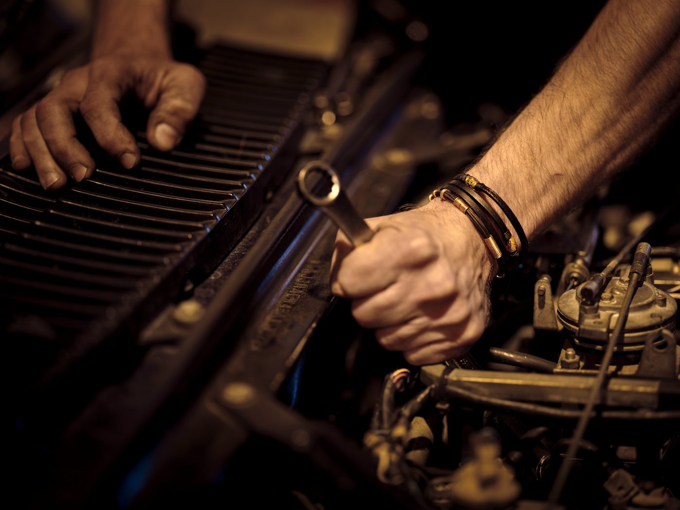 Hands with a wrench working on a car engine
